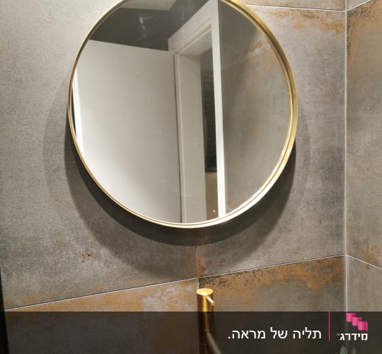 ברז זהב מותקן על קיר אריחים אפור